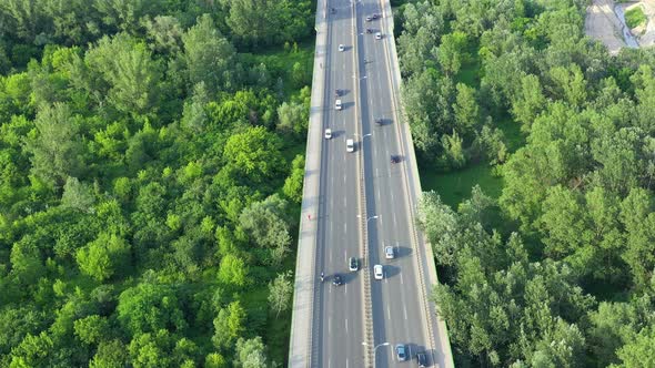 Aerial view of car traffic on modern bridge over river in city in summer day alt