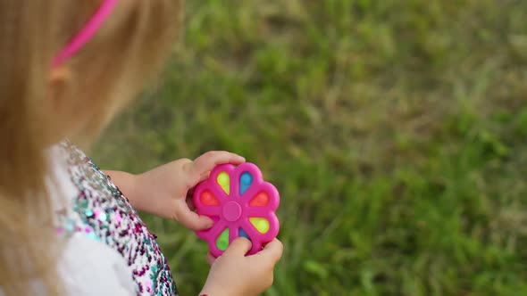 Closeup of Girl Playing Spinning with Pop It Sensory Antistress Toy in Park Stress Anxiety Relief alt
