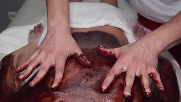 Closeup of Masseur Doing Massage with Chocolate Scrub alt