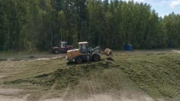 Drone view of tractors tamp the silage in the Silo Trench next to the forest 08 alt