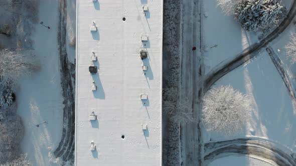 Aerial Top View Person Walking Next to Snow Covered Building Roof Winter Day alt