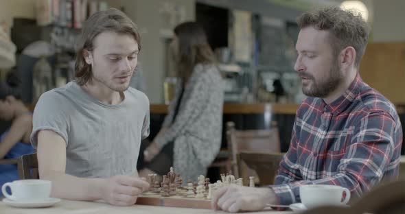 Men talking and playing chess while sitting in pub