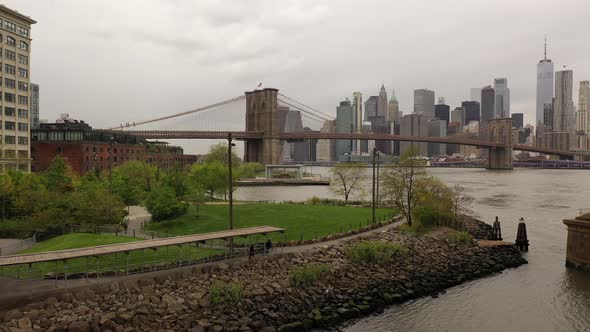 A low angle view over the East River on a cloudy day. The drone dolly in under the Manhattan Bridge, alt