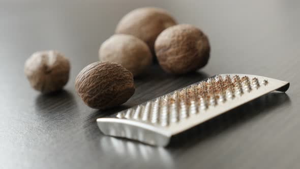 Nutmeg fruit and spice on wooden table shallow DOF slow pan 4K 2160p 30fps UltraHD footage - Myristi alt