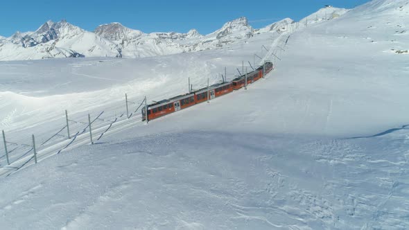 Cog Railway Train in Sunny Winter Day. Swiss Alps. Switzerland. Aerial View alt