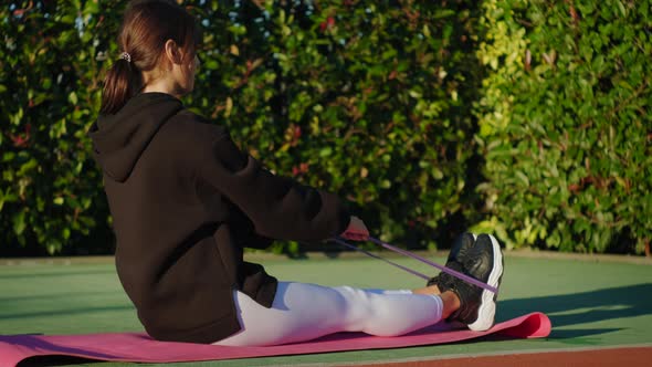 Lady Doing Forward Bends While Sitting on a Sports Mat Outdoors alt