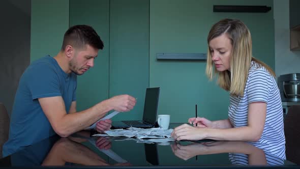 Man and Woman Looking at Payment Bills in the Kitchen alt