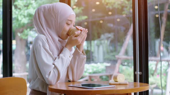 Young beautiful Asian Muslim women enjoying a relaxing moment working and playing with mobile phone alt