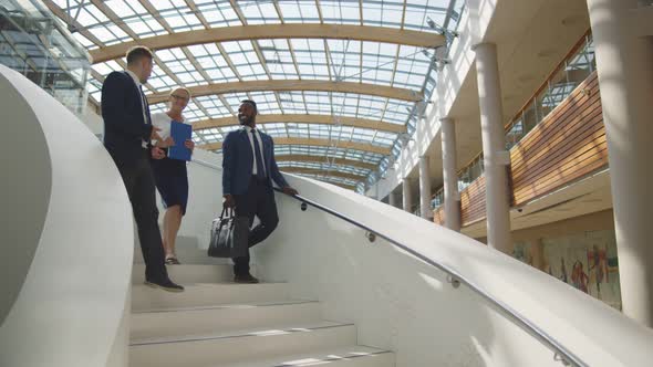 Multiethnic Business People Walking Downstairs Discussing Presentation alt