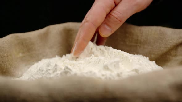Human hand touching a wheat powder powder in a sac