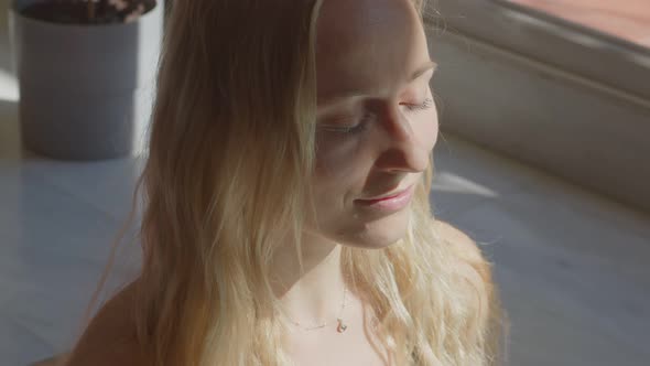 Beautiful Blond Caucasian Young Woman is Making Meditation Opening Eyes and Turning the Head to the