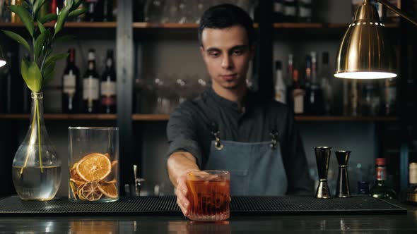 Close Up Shot of Bartender Hands Preparing Negroni Cocktail with Grapefruit alt