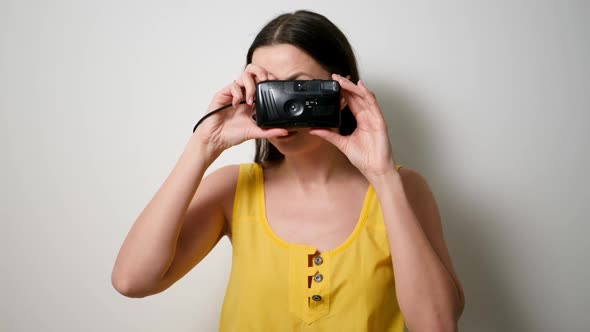 Girl Photographer in a Yellow T-shirt Takes a Soap Dish on an Old Plastic Camera alt