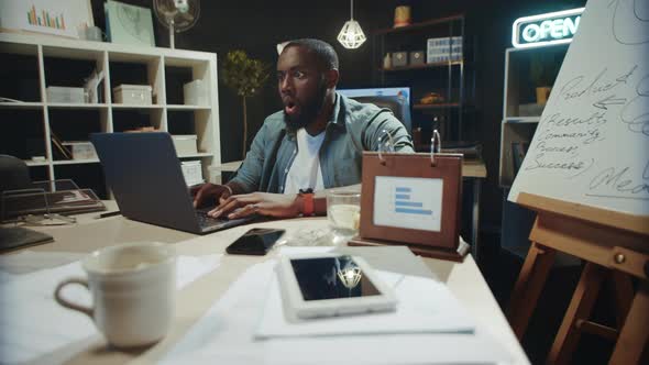 Excited African Guy Looking Laptop in Office. Afro Man Receiving Great News alt