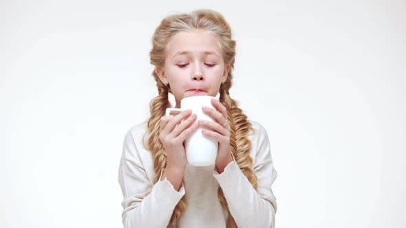 Small Caucasian Beautiful Caucasian Girl with Luxurious Long Blonde Hair Drinking Hot Milk From Cup alt