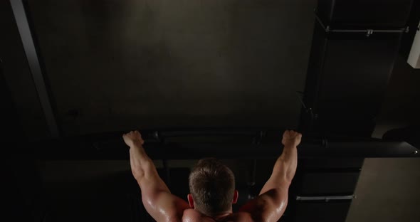 A man with beautiful muscles on his back, in the gym, pulls himself up on a horizontal bar alt