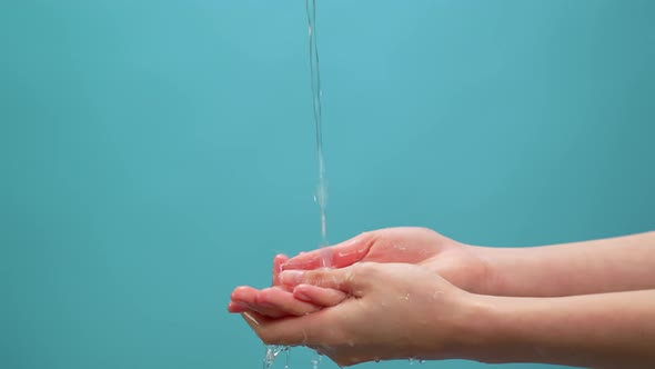 Splash of clean water flows into the hands on the blue background