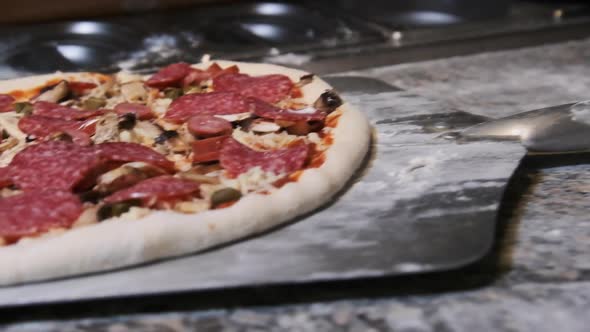 Chef Uses a Spatula To Pick Up Finished Pizza Dough for Baking. Slow Motion alt