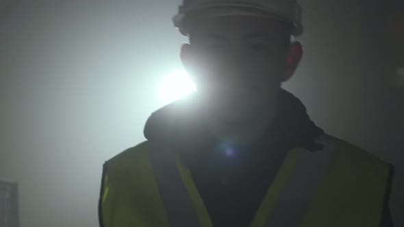 Portrait of the Engineer in the Builders Uniform and Helmet Going To the Camera on a Black alt