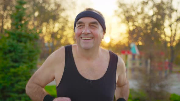 Senior Man Running on Road in Public Park alt