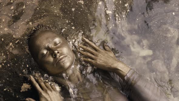 Art and Fashion Shot of Young Woman with Skin and Hair Covered By Golden Shiny Dye in Shallow alt