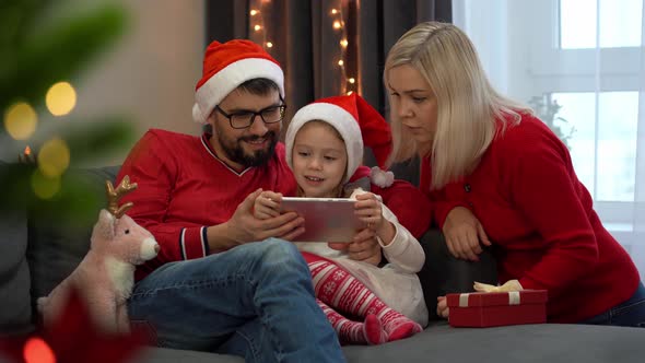 Family Choose New Years Gifts in Online Store By Tablet Next to Christmas Tree