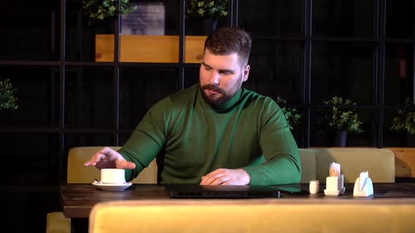 Hipster Checks the Time on His Watch and Drinks Coffee