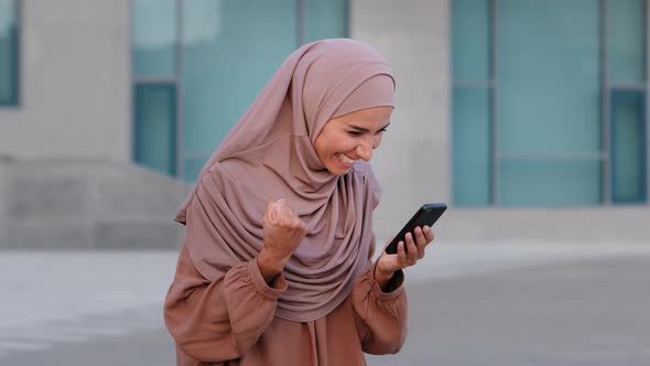 Portrait of Happy Muslim Business Woman Enjoy Success on Mobile Phone Outdoors alt
