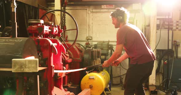 Bladesmith working with hot steel at kiln and press alt