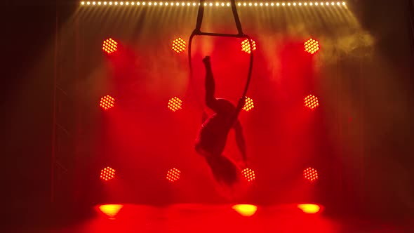 Flexible Pretty Brunette Woman in a Purple Tight Fitting Suit Performs Acrobatic Elements in an Air alt