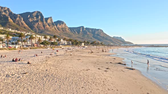 Beachgoers enjoying a lovely sunset on Camps Bay beach with a mountain backdrop