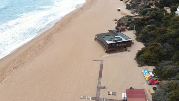 4k drone footage following a coastline sandy beach and tilt revealing the popular town of Albufeira alt