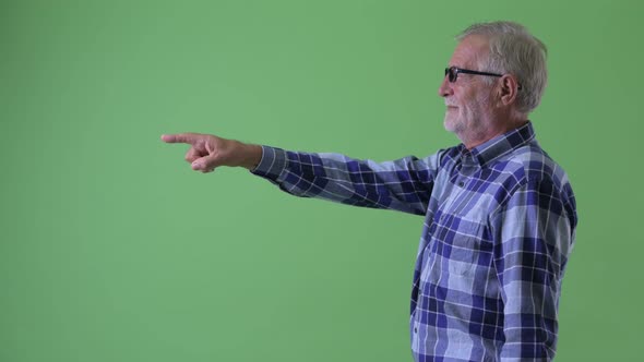 Profile View of Happy Senior Bearded Hipster Man Pointing Finger alt