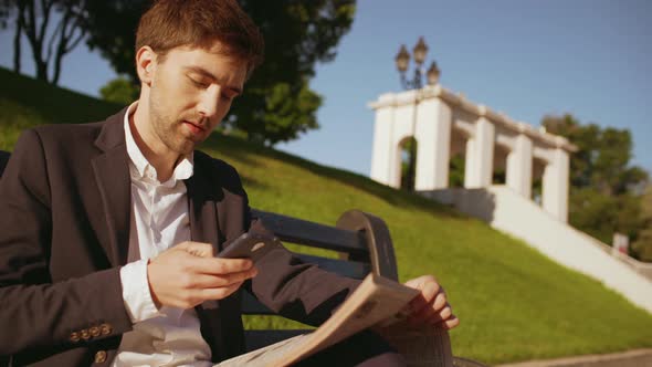 Slow Motion Handsome Salesman Business Man in Suit Sitting on Bench in Green Park on Sunny Day