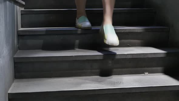 Women's Legs Go Down the Stairs at Night By the Light of a Street Lamp