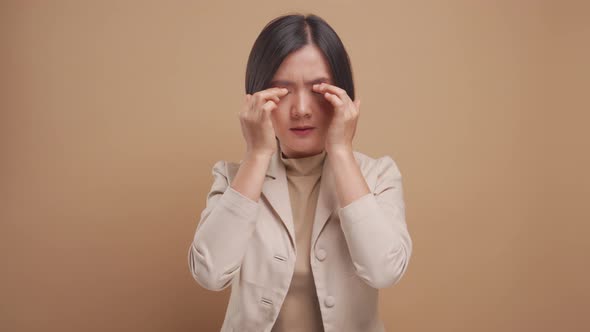 Asian business woman has headache standing isolated over beige background. 4K video