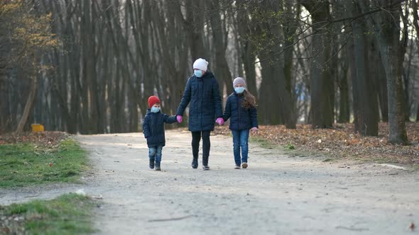 Mother, son and daughter walk in the Park in medical masks in the spring. 