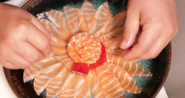 Putting Roe To A Platter Of Salmon Sashimi In A Sushi Restaurant - overhead shot alt