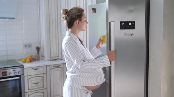 Young Pregnant Woman Looking Into Refrigerator For Something To Eat alt