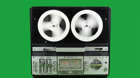 Rewinding Tape On An Old Reel To Reel Recorder On A Green Background.