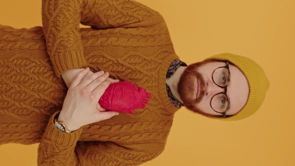 Vertical Shot of a Serious Caucasian Bearded Millennial Guy in Eyewear and a Beanie Holding Red alt