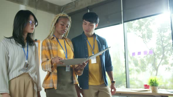 Smiling hipster friends in casual wear walking in modern workplace alt