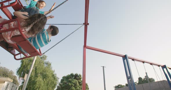 Children swinging together at a public playground alt