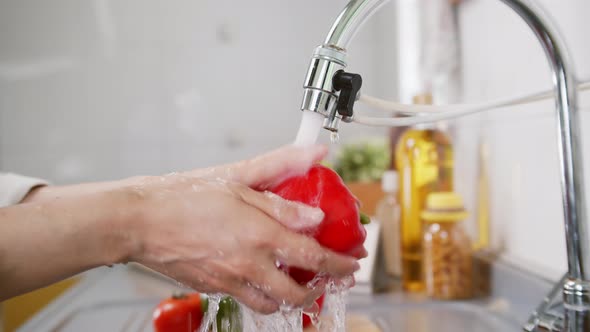 Close up of Woman Hand Tap water Washing a Fresh Organic Bell Pepper