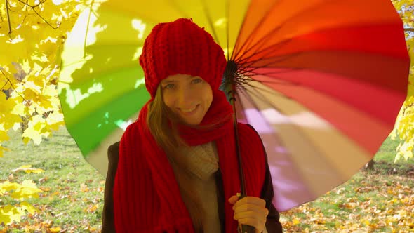 Beautiful Happy Woman Stands with an Umbrella in the Park and Smiles