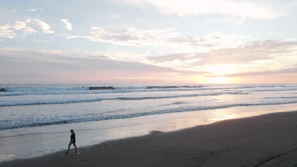 Young woman walking along a dream beach in the tropics at sunset then exiting the frame while many l alt