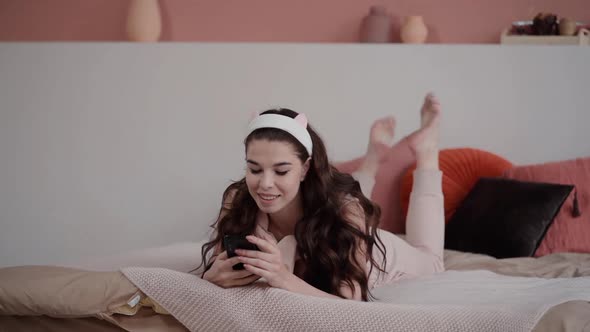 Woman Sit on Bed and Read News Text Messages Scrolling Feed on Phone. Feminine Teenager Woman