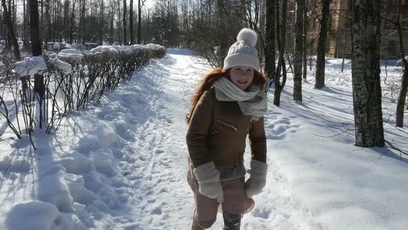 Ginger-Haired Girl Walking At Snowy Park. Redhead Teenage Child Having Fun On Winter Walk
