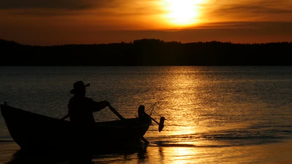 Silhouette of man rowing on Boat at Sunset