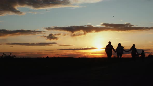 Silhouettes of Happy Family Walk at Sunset